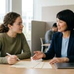 Build an Internship Portfolio Without Sharing Confidential Work Intern discussing a portfolio concept with a workplace mentor at a meeting table.